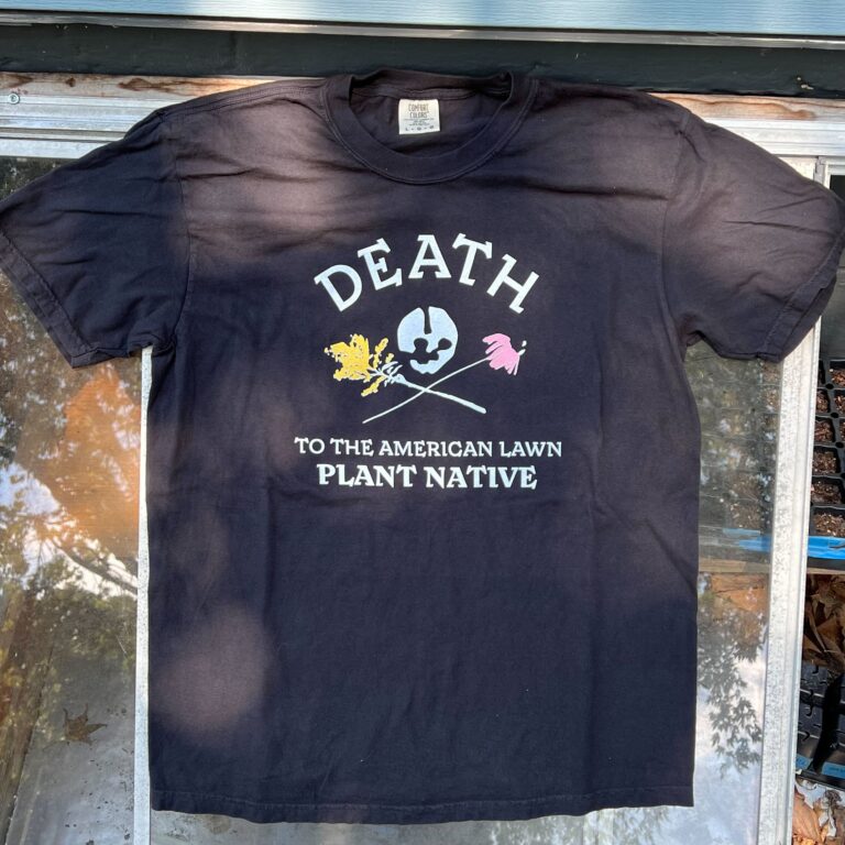 Black tshirt that reads Death to the American Lawn, Plant Native in all caps white text with a skull and coneflower and goldenrod "crossbones"